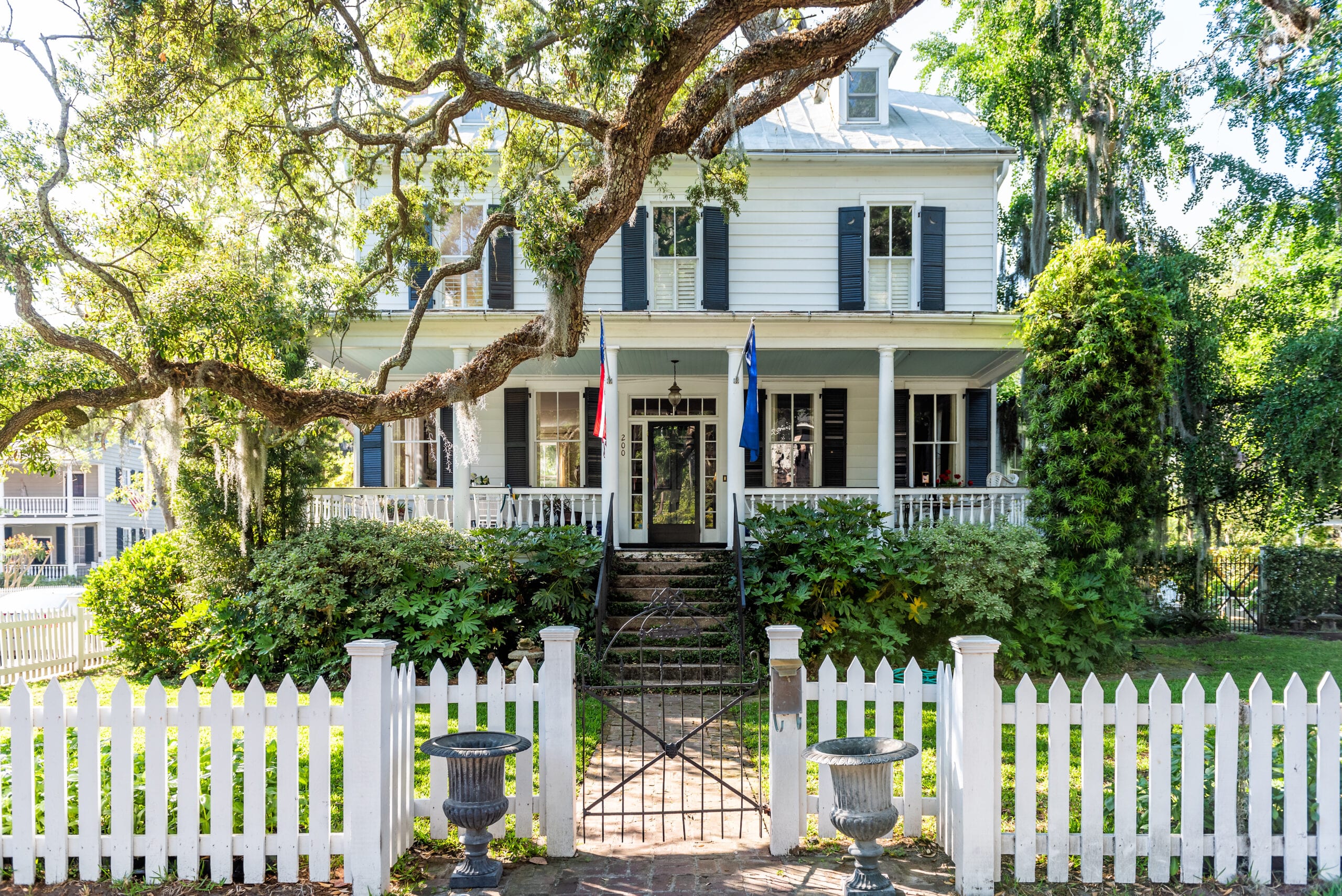 Mount Pleasant, USA - May 11, 2018: Typical American residential house building in Charleston, South Carolina area with American flag and white picket fence